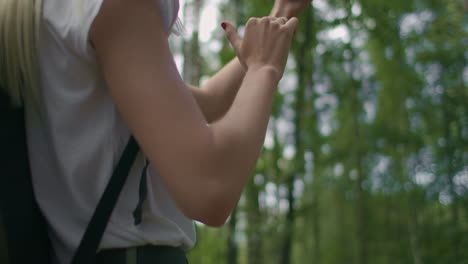 Close-up-of-a-woman-holding-a-mobile-phone-walking-through-the-woods-traveling-with-a-backpack-in-slow-motion.-Navigate-through-the-forest-using-the-Navigator-in-your-mobile-phone